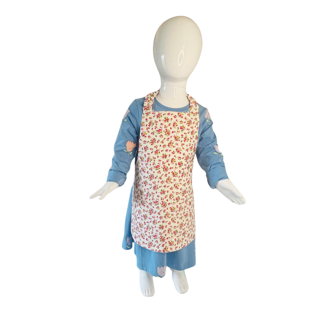 A toddlers apron and matching oven mitt set. Pattern is white with pink and yellow dainty flowers all over. Styled on a mannequin.