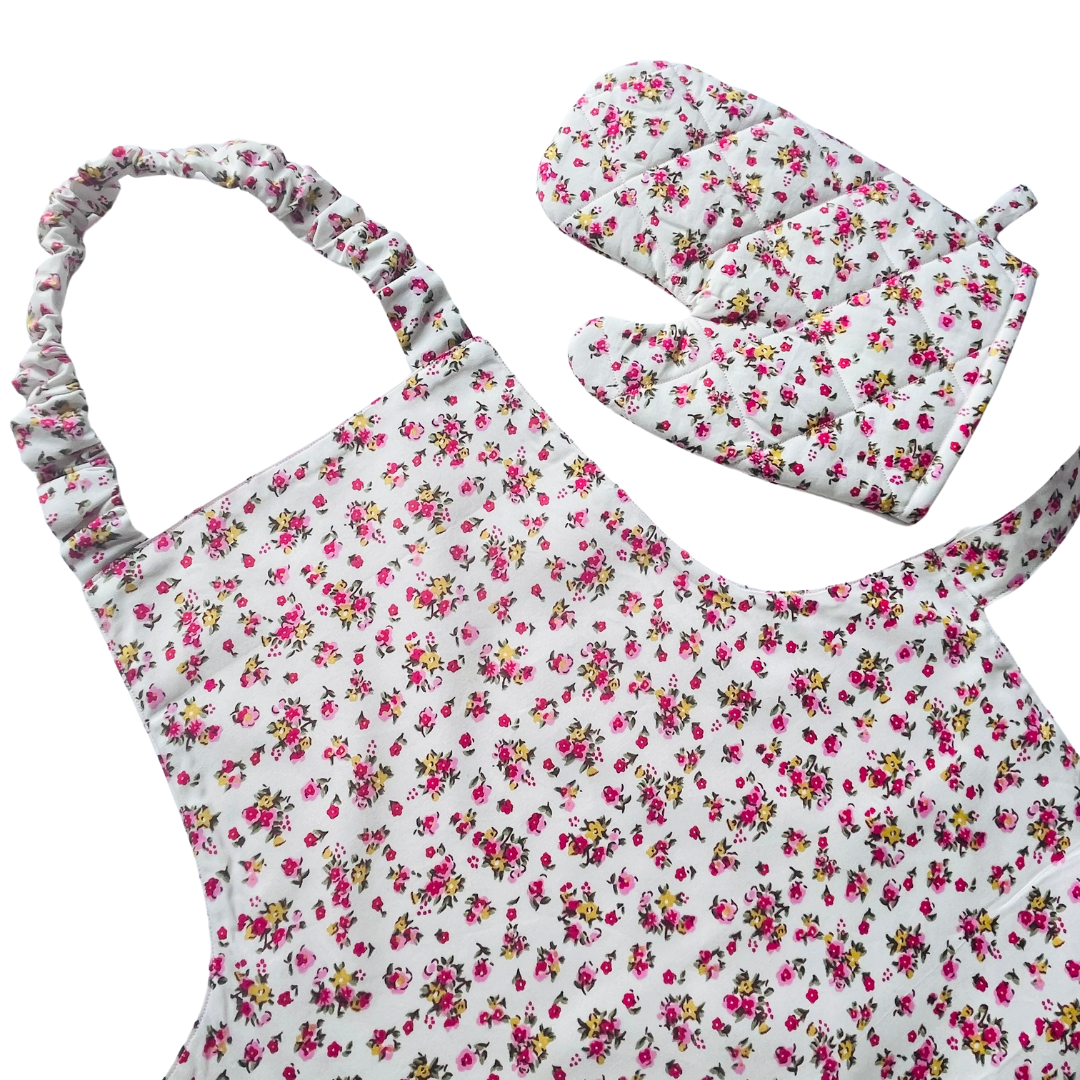A toddlers apron and matching oven mitt set. Pattern is white with pink and yellow dainty flowers all over.