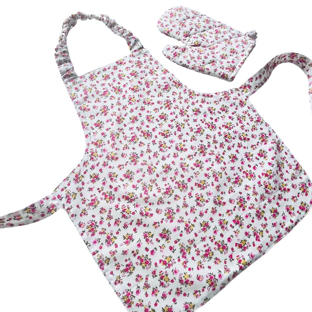 A toddlers apron and matching oven mitt set. Pattern is white with pink and yellow dainty flowers all over.
