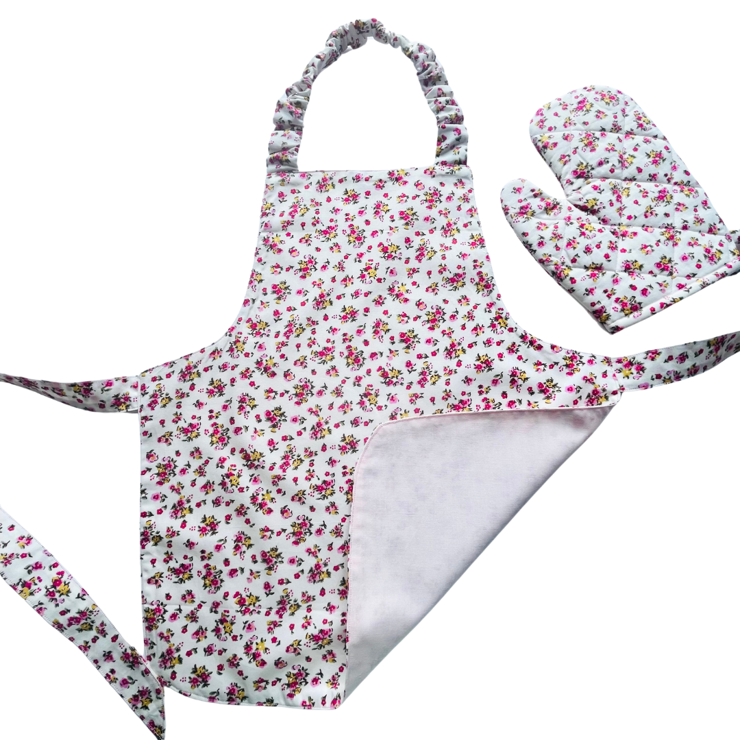 A toddlers apron and matching oven mitt set. Pattern is white with pink and yellow dainty flowers all over.