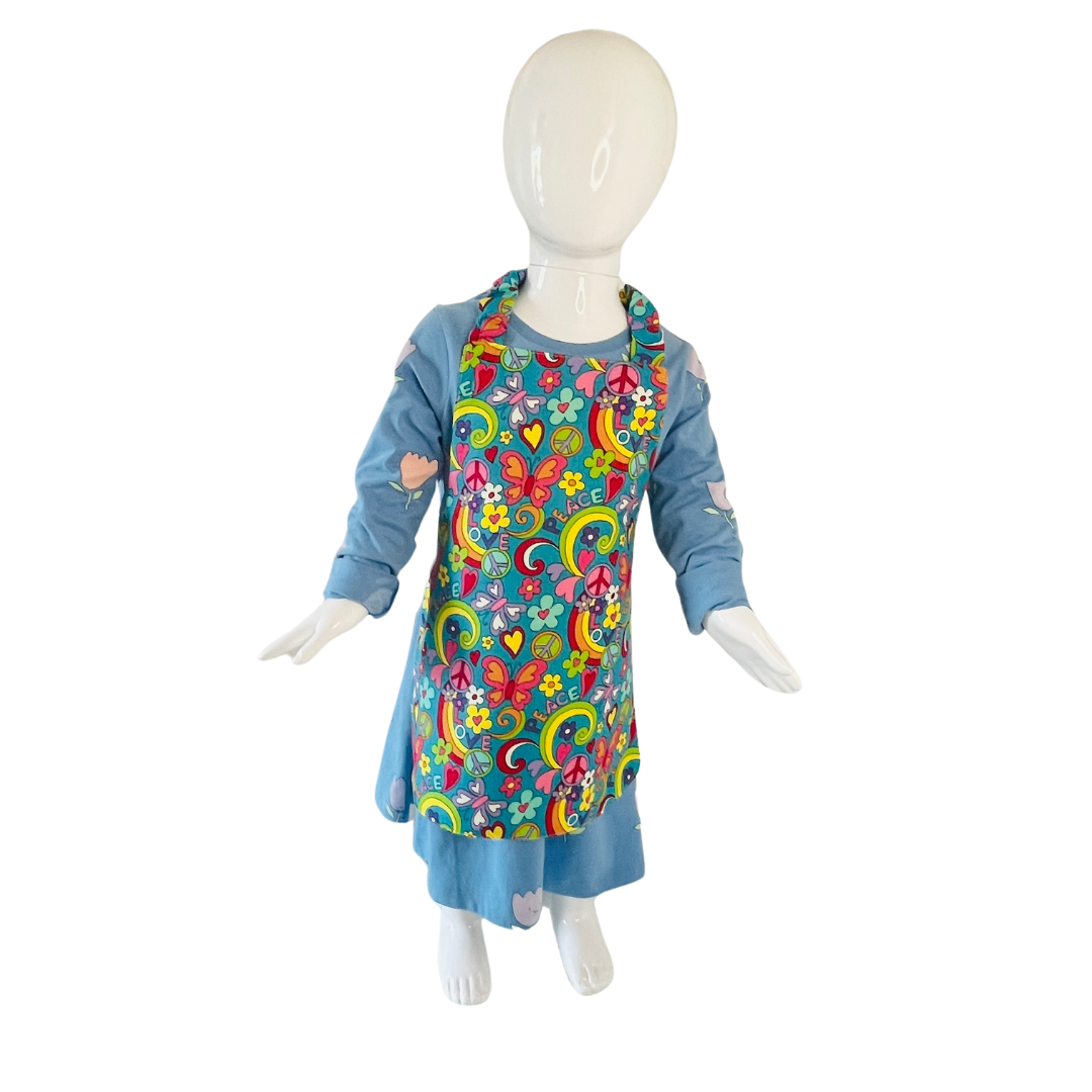 A child’s apron and matching oven mitt set. Pattern is turquoise with brightly coloured 60s inspired funky pictures all over. Styled on mannequin.