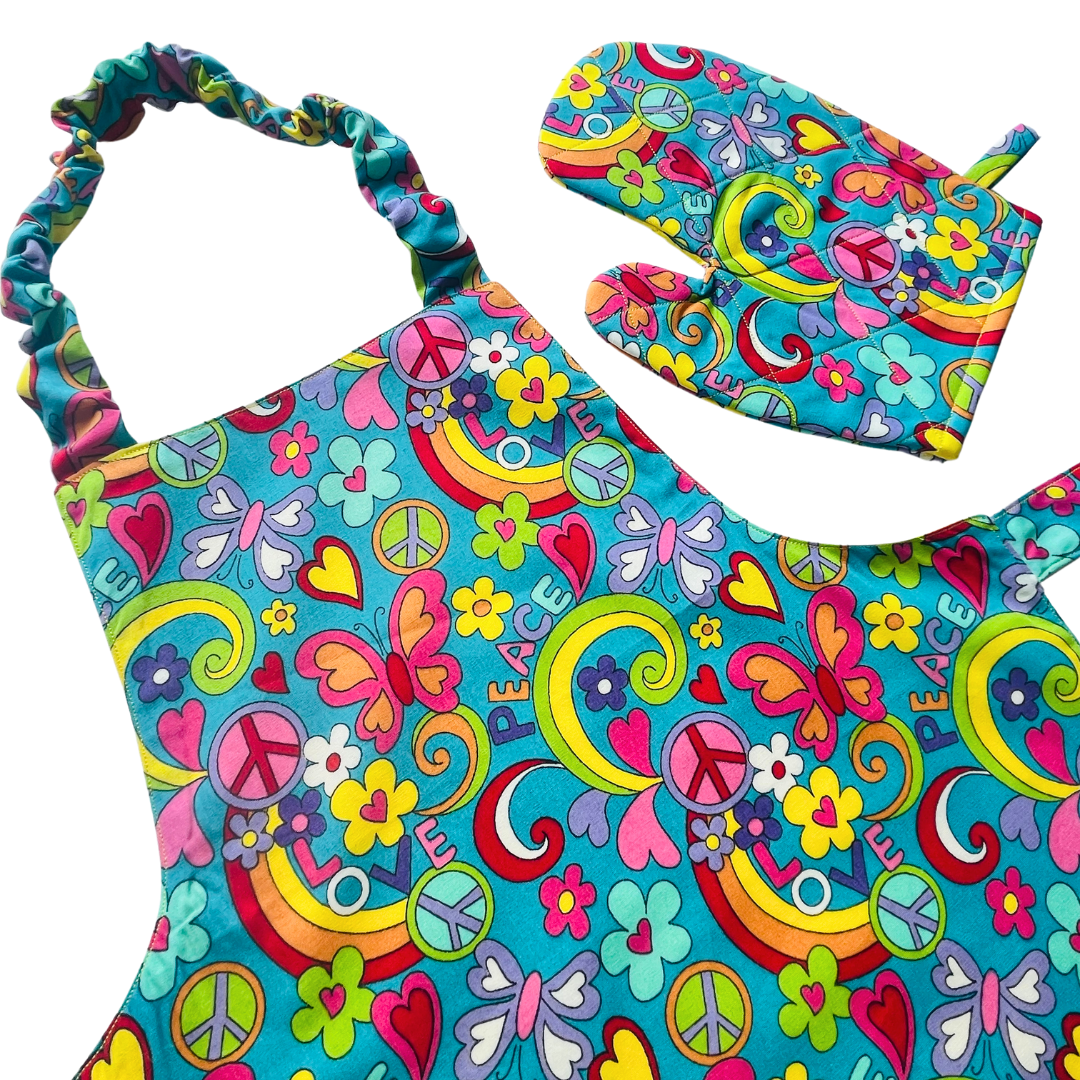 A child’s apron and matching oven mitt set. Pattern is turquoise with brightly coloured 60s inspired funky pictures all over.
