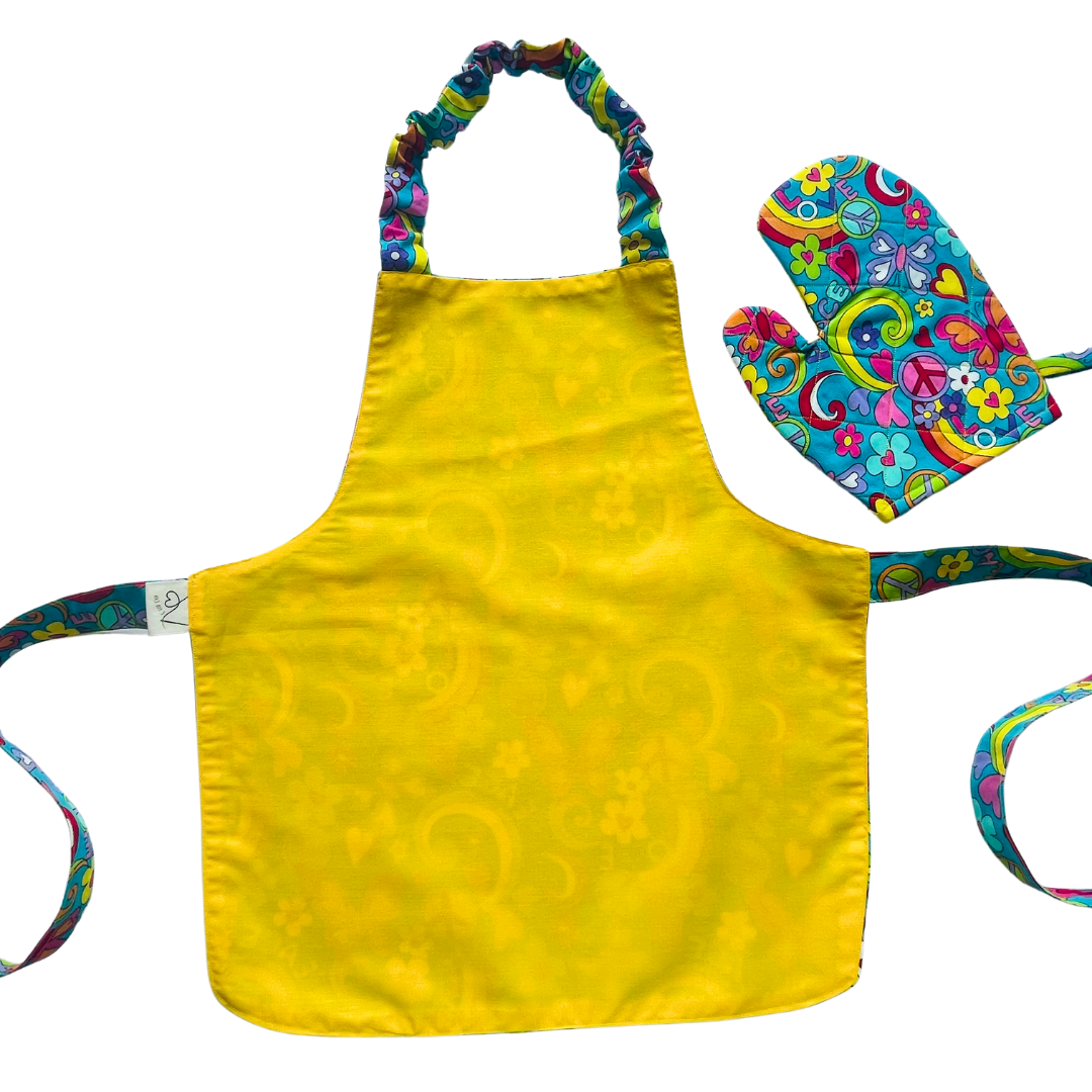 A child’s apron and matching oven mitt set. Pattern is turquoise with brightly coloured 60s inspired funky pictures all over.