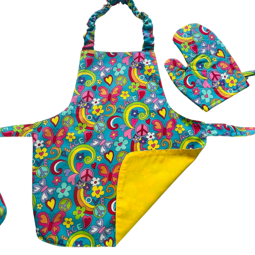 A child’s apron and matching oven mitt set. Pattern is turquoise with brightly coloured 60s inspired funky pictures all over.