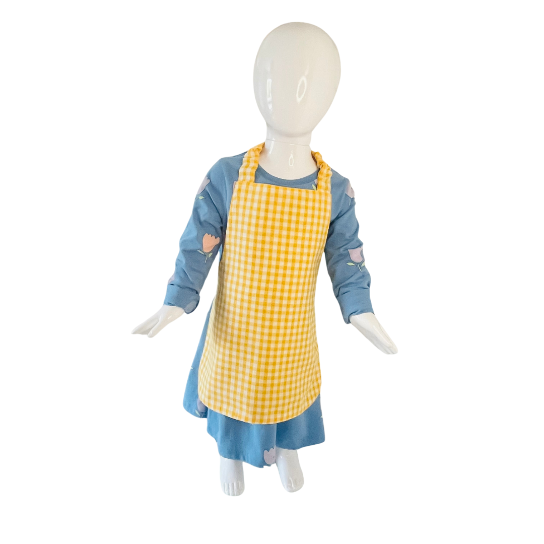 A child’s apron and matching oven mitt set. Pattern is yellow and white gingham. Styled on mannequin.