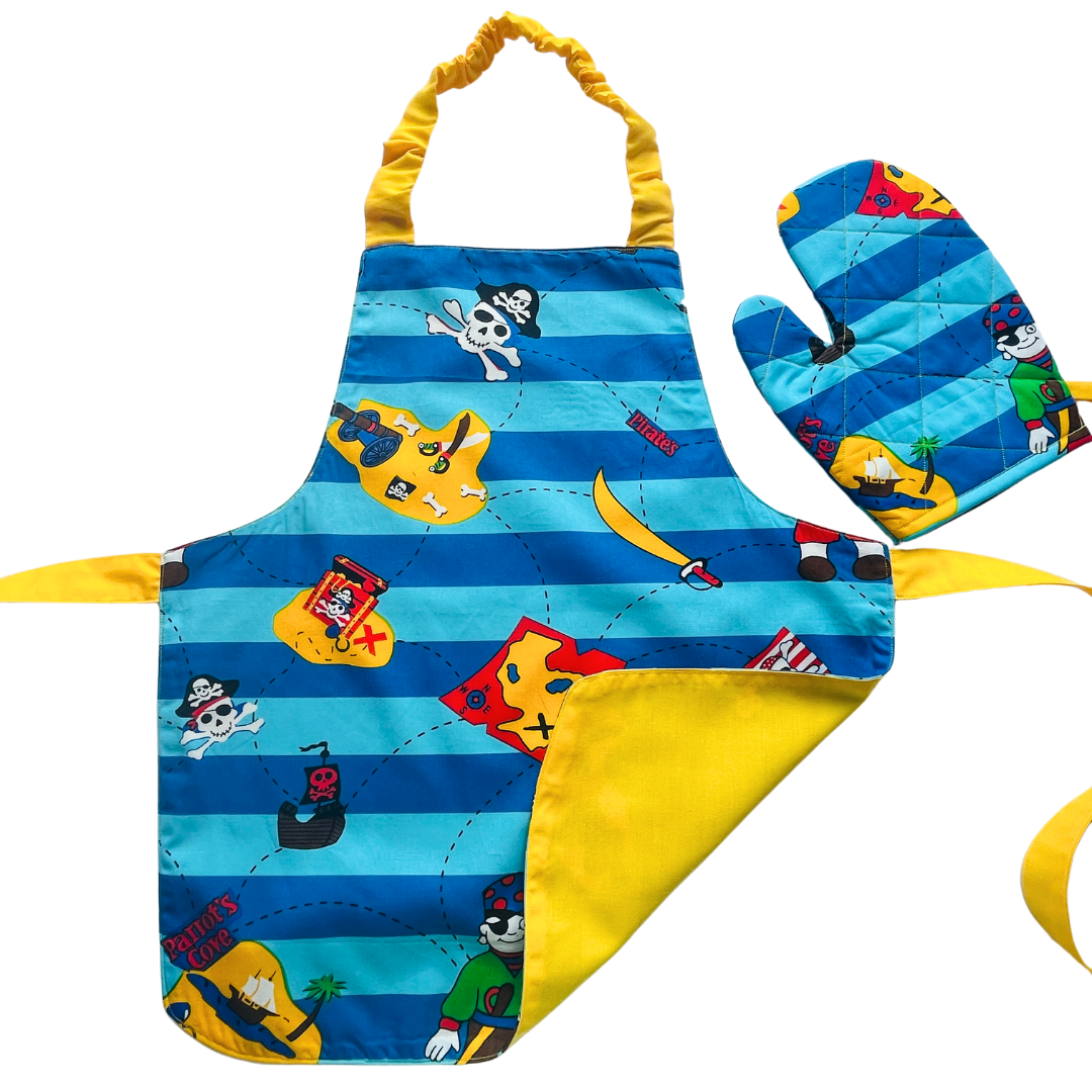 A child’s apron and matching oven mitt set. Pattern is light and dark blue with yellow and has pirate pictures such as treasure, maps and ships all over.
