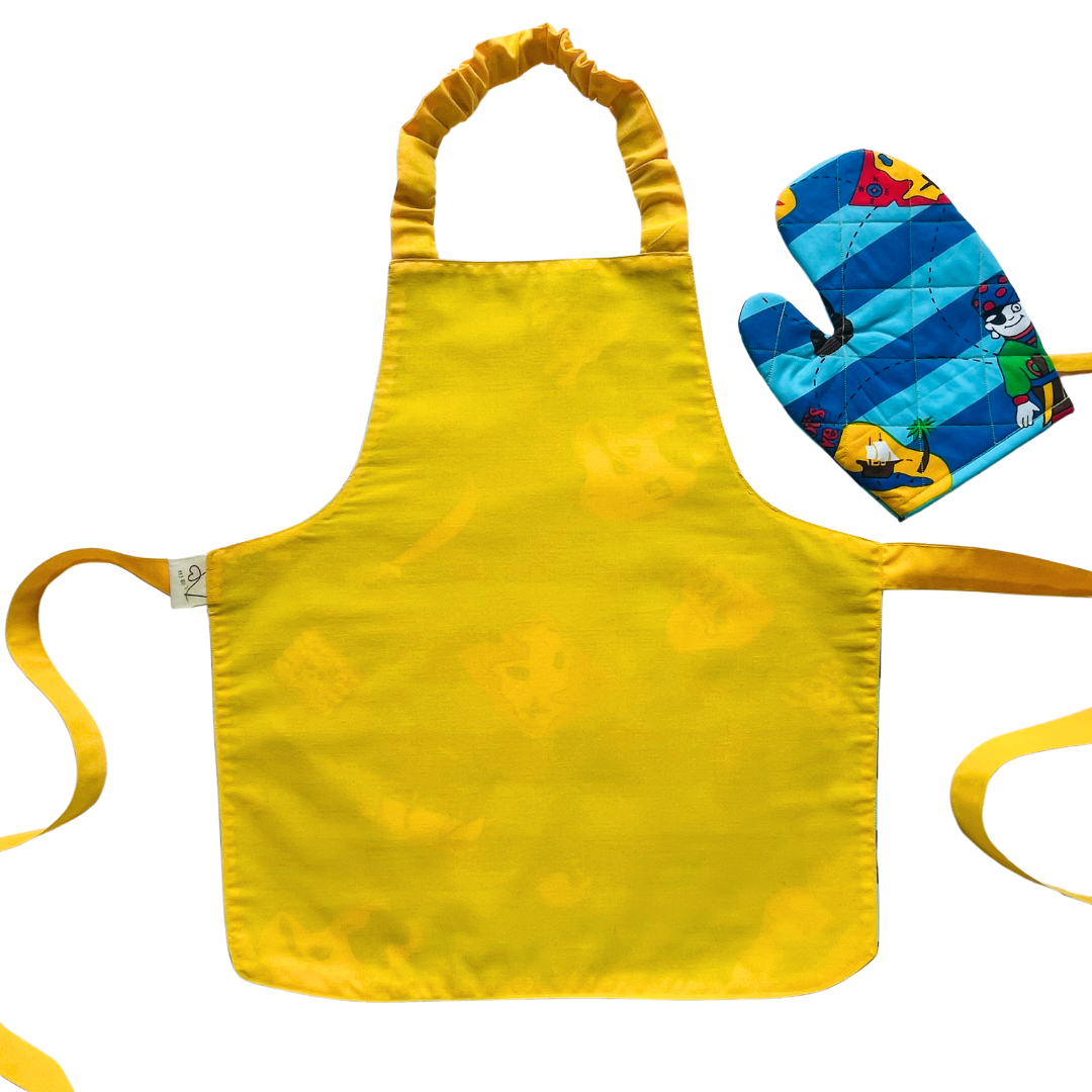 A child’s apron and matching oven mitt set. Pattern is light and dark blue with yellow and has pirate pictures such as treasure, maps and ships all over.