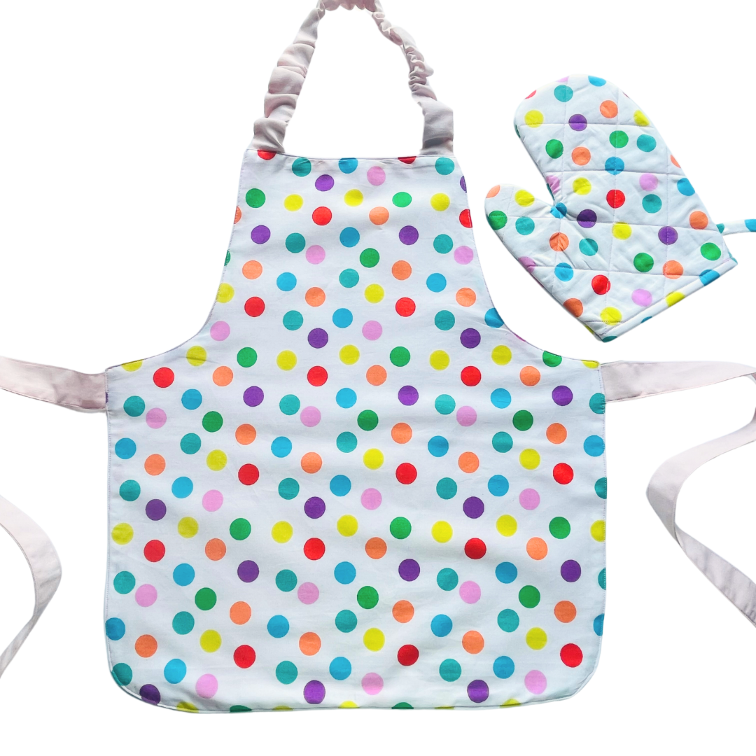 A child’s apron and matching oven mitt set. Pattern is white and pale pink and has multicoloured spots all over.