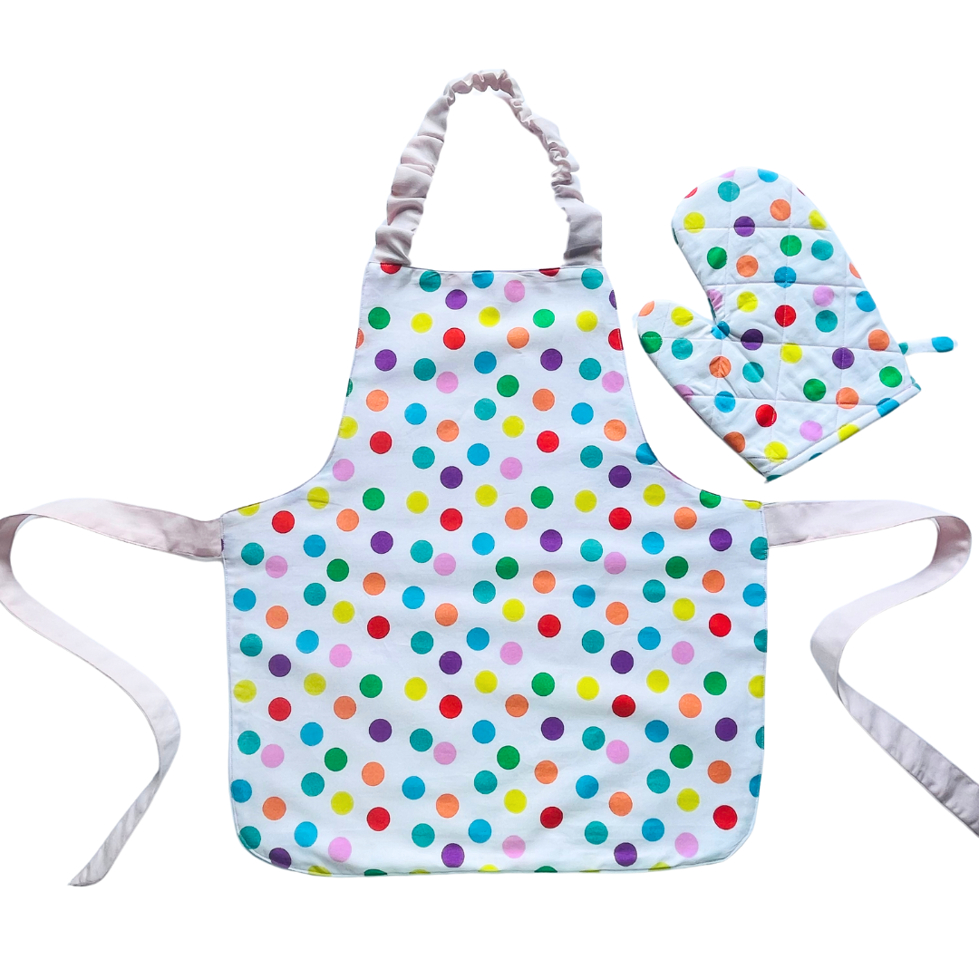 A child’s apron and matching oven mitt set. Pattern is white and pale pink and has multicoloured spots all over.