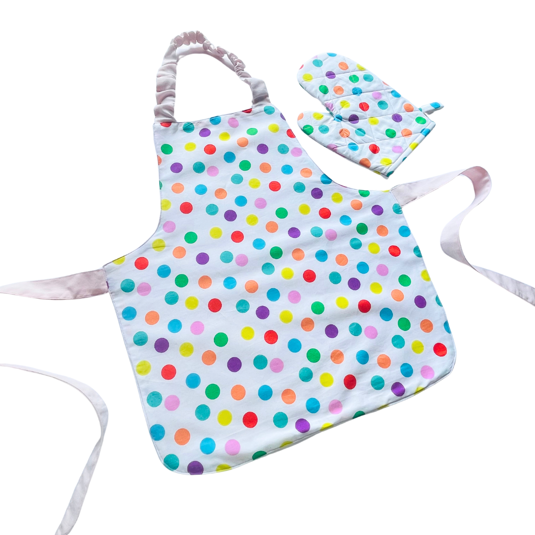A child’s apron and matching oven mitt set. Pattern is white and pale pink and has multicoloured spots all over.