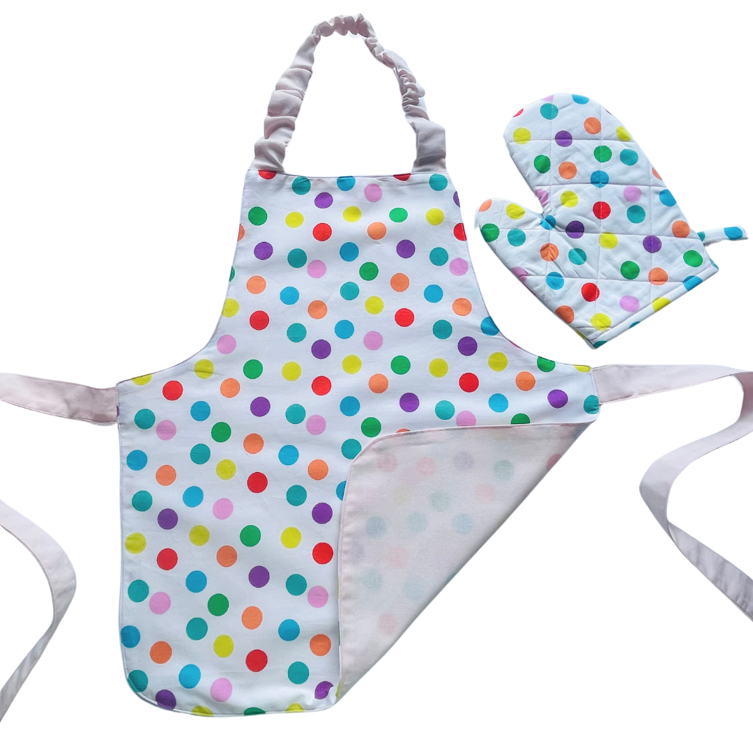 A child’s apron and matching oven mitt set. Pattern is white and pale pink and has multicoloured spots all over.