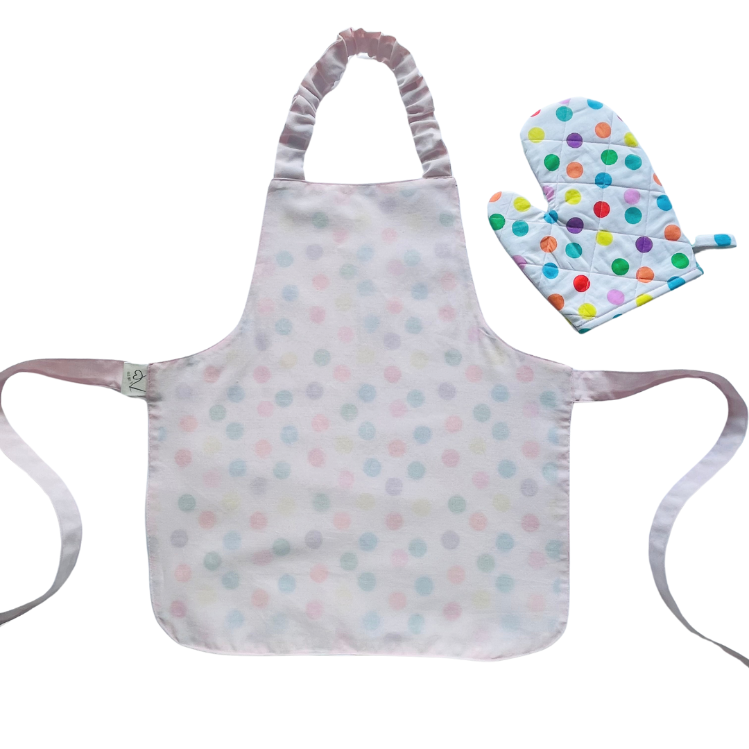 A child’s apron and matching oven mitt set. Pattern is white and pale pink and has multicoloured spots all over.
