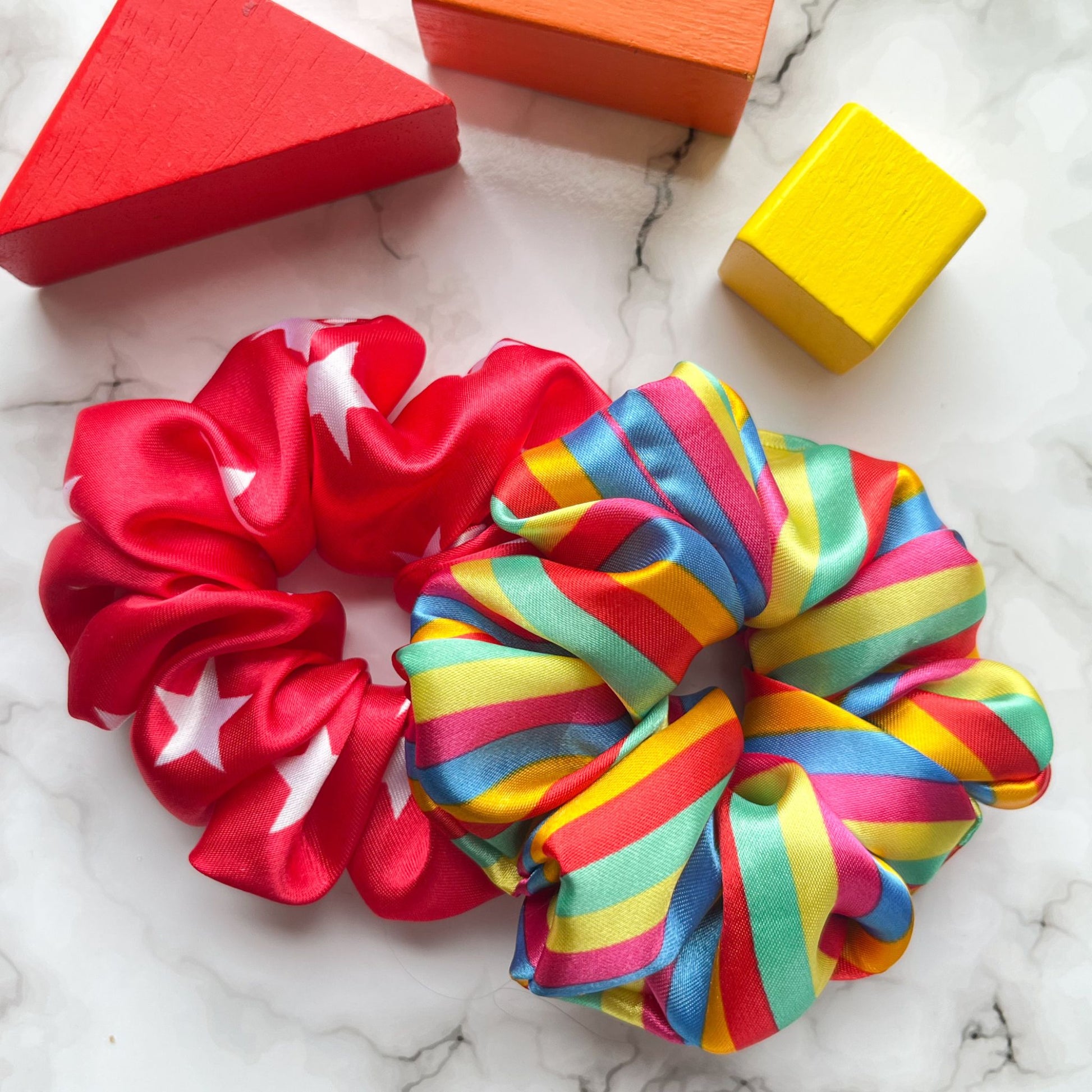 Styled overview of circus star and striped rainbow hair scrunchies satin E for Eva