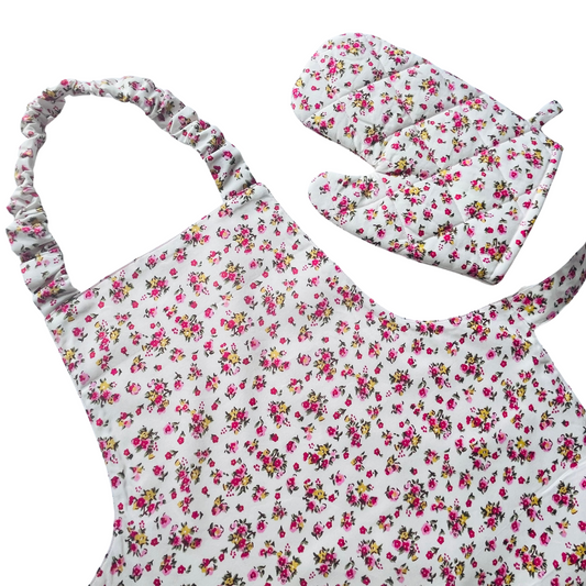A toddlers apron and matching oven mitt set. Pattern is white with pink and yellow dainty flowers all over.